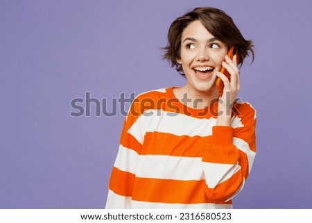 Young fun woman she wear casual clothes sweatshirt talk speak on mobile cell phone conducting pleasant conversation isolated on plain pastel light purple background studio portrait. Lifestyle concept
