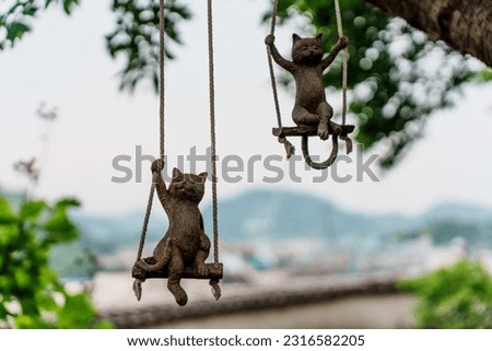 Pictures of cat figurines holding onto swings.