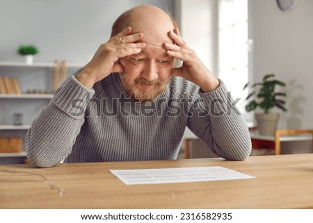 Retired old man with Alzheimer's disease can't remember letters and numbers. Senior man with dementia sitting at desk, holding head and looking at calendar with confused, worried face expression Royalty-Free Stock Photo #2316582935