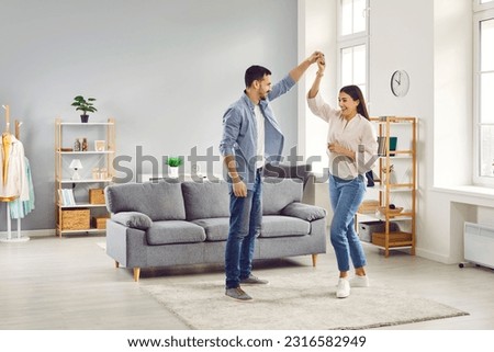 Happy loving romantic couple dancing together in living room. Full length shot of attractive young woman and man celebrating relocation, anniversary or enjoying spending time together at home Royalty-Free Stock Photo #2316582949