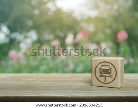 Service fix car with wrench tool icon on wood block cube on wooden table over blur pink flower and tree in park, Business repair car service concept