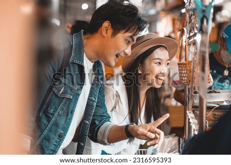 Asian couple tourist backpacker enjoying and eating street food in night market with crowd of people at Yaowarat road, Bangkok, Thailand Royalty-Free Stock Photo #2316595393