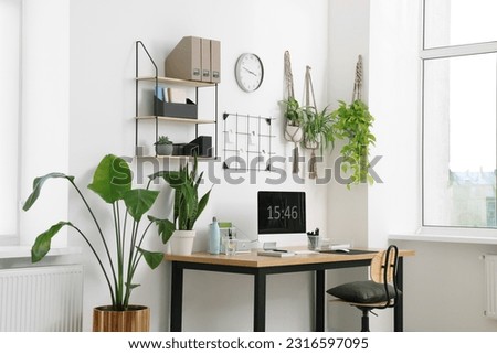 Cozy workplace with computer, modern furniture and houseplants at home Royalty-Free Stock Photo #2316597095