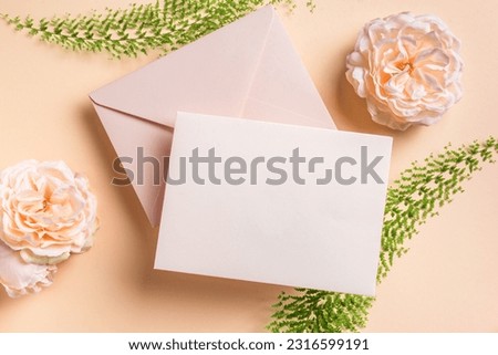 Greeting or invitation blank card, rose flowers and fern leaves on pink pastel background, copy space. Stylish creative mock up, romantic wedding or holiday celebration concept.