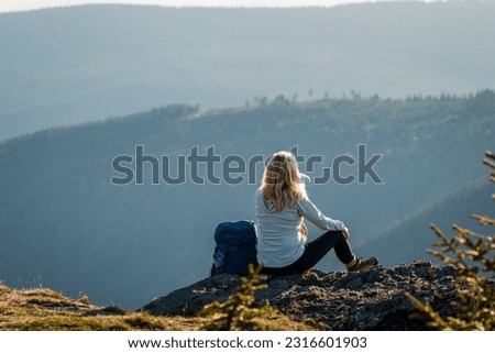 Woman with backpack relax on rock after successfully climbed mountain summit