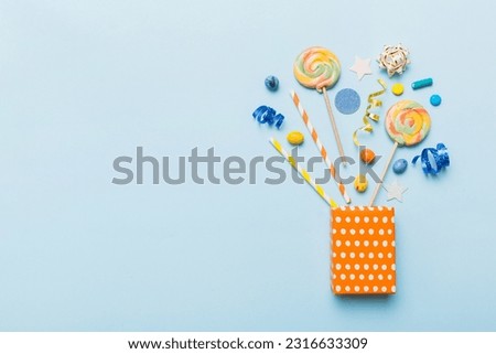 gift box in corner full of assorted traditional candies falling out on colored background with copy space. Happy Holidays sale concept.