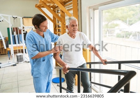 Senior man with physiotherapist training walking in rehab clinic Royalty-Free Stock Photo #2316639805