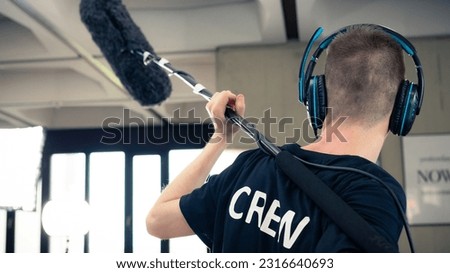 This photograph portraits a boom operator working on a filmset.