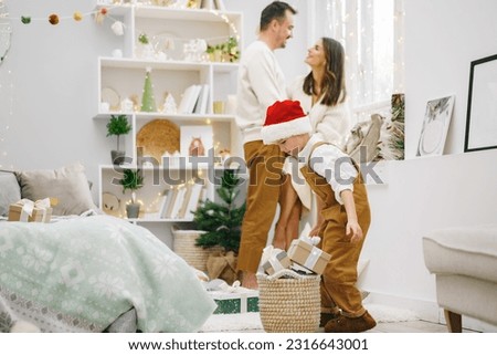 Parent and their little son having fun and playing together indoors at Christmas time