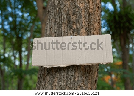 Crate paper sign on the tree for writing environmental campaign messages and forest conservation, for example, do not cut trees, plant conservation areas, love the world, love trees, etc.             