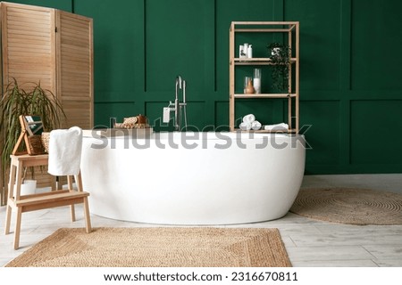 Interior of bathroom with bathtub, mirror on stepladder and folding screen