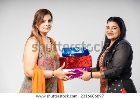 Indian woman giving gift to each other on white background.