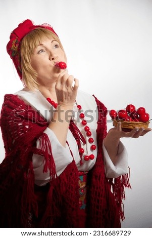 Portrait of heerful funny adult mature woman solokha with red berries. Female model in clothes of national ethnic Slavic style. Stylized Ukrainian, Belarusian or Russian woman in comic photo shoot
