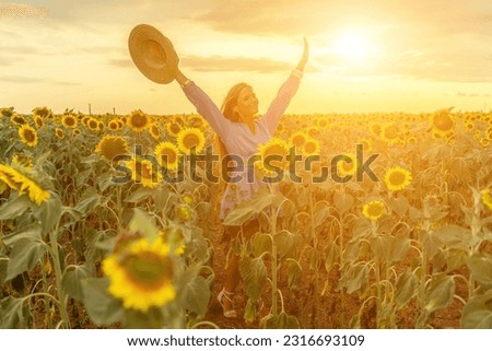 Woman sunflower field. Happy girl in blue dress and straw hat posing in a vast field of sunflowers at sunset. Summer time. Royalty-Free Stock Photo #2316693109