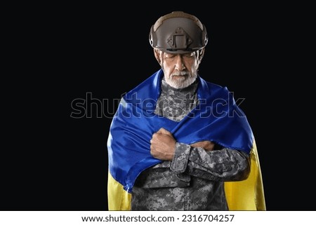 Mature soldier with flag of Ukraine on dark background
