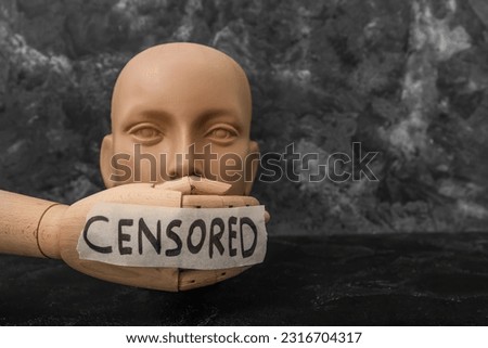 Taped wooden hand with word CENSORED and human head on dark table Royalty-Free Stock Photo #2316704317