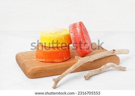 Board with different handmade solid shampoo and branches on light background, closeup