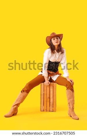 Beautiful cowgirl sitting on yellow background