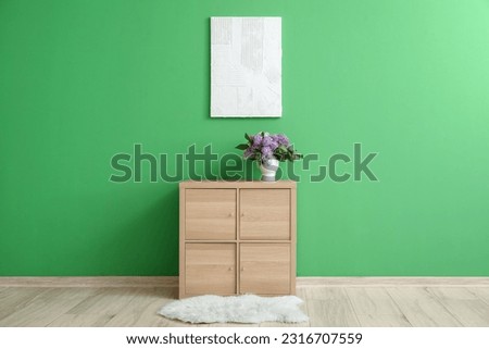 Interior of room with cabinet and bouquet of lilac flowers