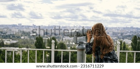 Banner back shot of a blonde woman looking to the city through some big sight seeing binoculars. Royalty-Free Stock Photo #2316711229
