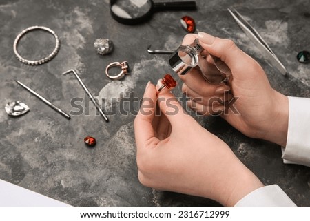 Female jeweler examining ring on dark table, closeup Royalty-Free Stock Photo #2316712999