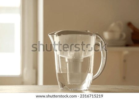 Water filter jug on table in kitchen Royalty-Free Stock Photo #2316715219