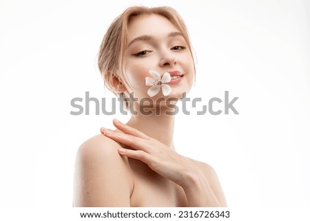 Beautiful blonde girl with clear and glowing skin with a white and pink flower in her mouth on a white background Royalty-Free Stock Photo #2316726343