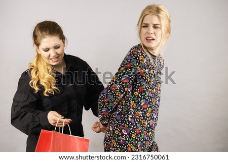 Shoplifting is a crime. Young fashionable woman being caught on stealing clothes by female security guard. Customer being thief. Royalty-Free Stock Photo #2316750061