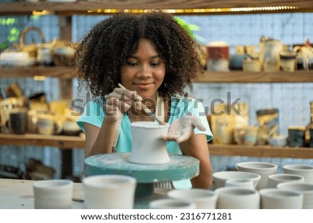 Creative afro American young woman artist molding clay form by hand finger on pottery wheel