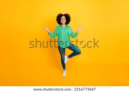 Mental health, harmony. Full length photo of a stylish lovely calm african american or brazilian curly woman meditating while standing tree pose with closed eyes on isolated yellow background