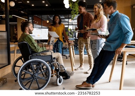Diverse male and female colleagues in discussion at casual office meeting. Casual office, teamwork, disability, inclusivity, business and work, unaltered. Royalty-Free Stock Photo #2316782253