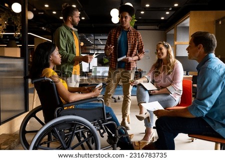 Diverse male and female colleagues in discussion in casual office meeting. Casual office, teamwork, disability, inclusivity, business and work, unaltered. Royalty-Free Stock Photo #2316783735