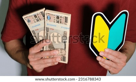A person with a beginner mark and a wad of money.
Translation: Bank of Japan, 10000, Bank of Japan, Common to financial institutions, National Printing Bureau. Royalty-Free Stock Photo #2316788343