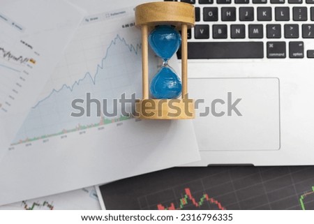 Clock alarm with stock graph chart in laptop screen background.Time,stock market,business success and investment concept.