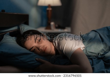 Young sad woman lying in bed late at night trying to sleep suffering insomnia. Girl in bed scared on nightmares looking worried and stressed. Sleeping disorder and insomnia concept Royalty-Free Stock Photo #2316796501