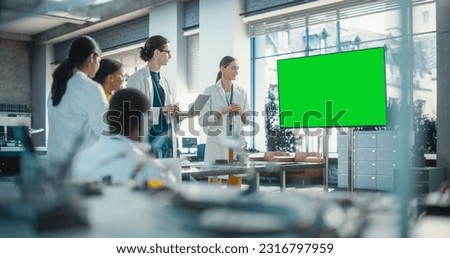 Group of Students Listening to Their Robotics Female Professor Who Uses Green Screen Monitor in a Laboratory. Team of Engineers Having Meeting and Discussing Manufacturing Ideas, Using Technology