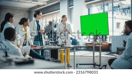 Group of Students Listening to Their Robotics Female Professor Who Uses Green Screen Monitor in a Laboratory. Team of Engineers Having Meeting, Discussing Manufacturing Ideas, Using High Technology