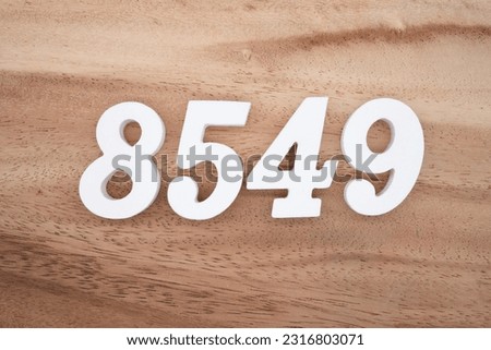 White number 8549 on a brown and light brown wooden background.