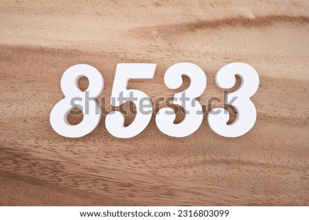 White number 8533 on a brown and light brown wooden background.