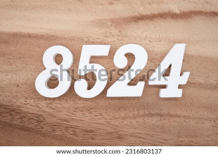 White number 8524 on a brown and light brown wooden background.