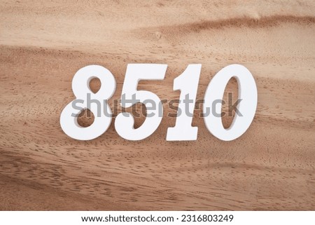 White number 8510 on a brown and light brown wooden background.