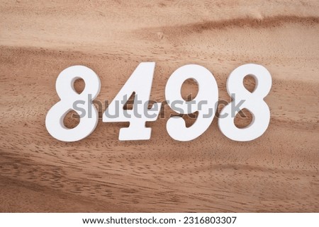 White number 8498 on a brown and light brown wooden background.