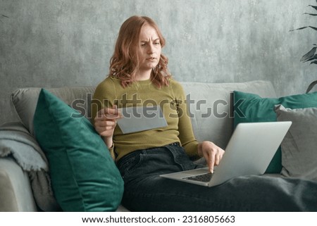 Focused young woman holding papers in her hands, calculating family budget, trying to save some money to buy new bicycle to her son, having stressed and concentrated look. High quality photo
