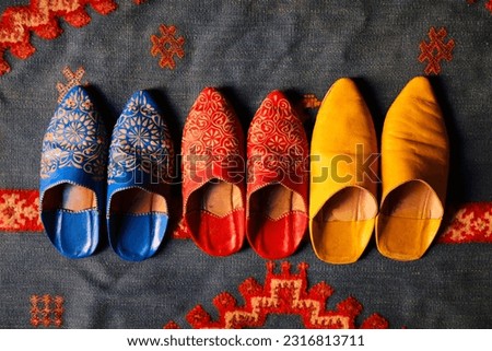 Moroccan handicraft. Traditional babouche leather footwear on ornamental Moroccan wool rug. Royalty-Free Stock Photo #2316813711