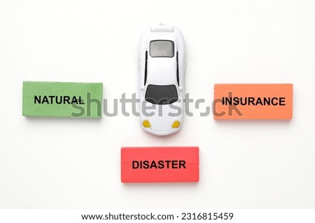 A picture of car diorama with natural disaster insurance word at wooden block on white background.