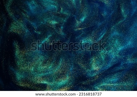 Various stains and overflows of gold particles in blue fluid with green tints. Golden particles dust and smooth defocused background. Liquid iridescent shiny backdrop with depth of field. Royalty-Free Stock Photo #2316818737