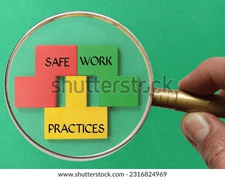 Magnifier glass on wooden puzzle with text SAFE, WORK and PRACTICES isolated green background. 