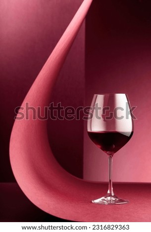 Glass of red wine on a red background. Copy space.