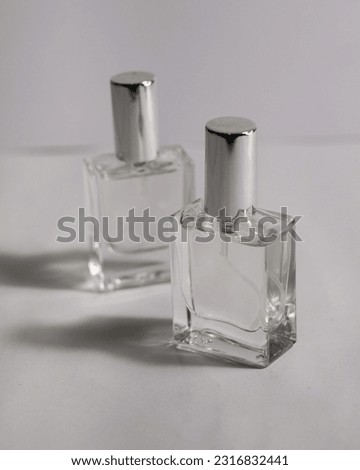 clear perfume bottle made of glass with silver cap on white background and black background. made for liquid perfume with spray.