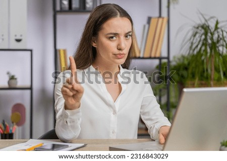 Caucasian young business woman working on laptop computer shakes finger, saying No be careful scolding and giving advice to avoid danger mistake disapproval sign at office. Confident freelancer girl